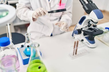 Young chinese woman wearing scientist uniform using loupe at laboratory