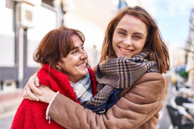 İki kadın anne ve kızı sokakta birbirlerine sarılıyorlar.