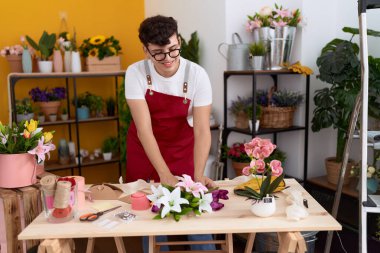 Non binary man florist make bouquet of flowers at flower shop