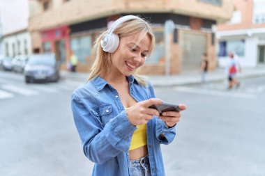 Sokakta video oyunu oynarken kendine güvenen genç sarışın kadın.