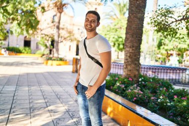 Parkta kendinden emin gülümseyen İspanyol genç adam.