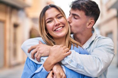 Genç adam ve kadın çift birbirlerine sarılıyor ve öpüşüyorlar.