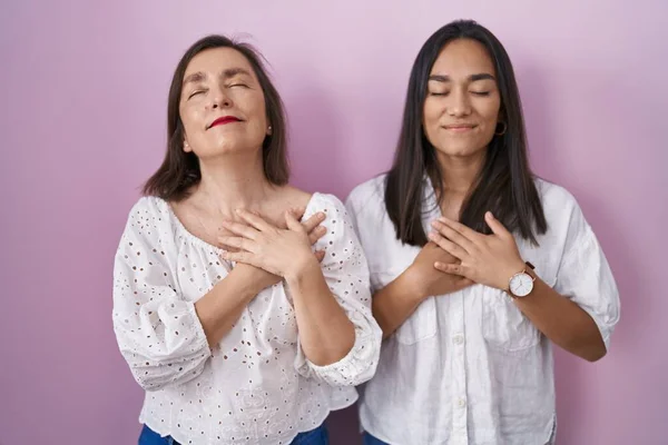 Hispanic Mother Daughter Together Smiling Hands Chest Closed Eyes Grateful — Zdjęcie stockowe