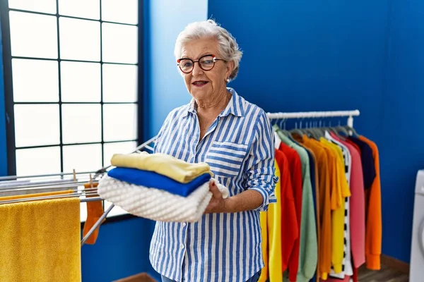 Starší Šedovlasá Žena Úsměvem Sebevědomě Drží Složené Oblečení Prádelně — Stock fotografie