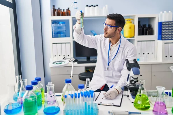 Laboratuvarda test tüpleri tutan genç İspanyol bilim adamı rapor yazıyor.