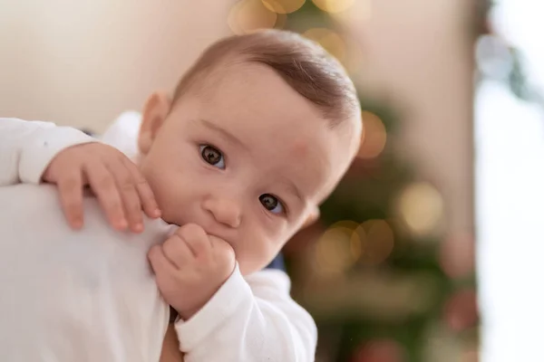 Adorable Toddler Sucking Fingers Standing Christmas Tree Mother Arms Home — Stock Photo, Image