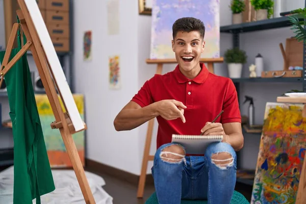 Young Hispanic Man Drawing Art Notebook Smiling Happy Pointing Hand — Stockfoto