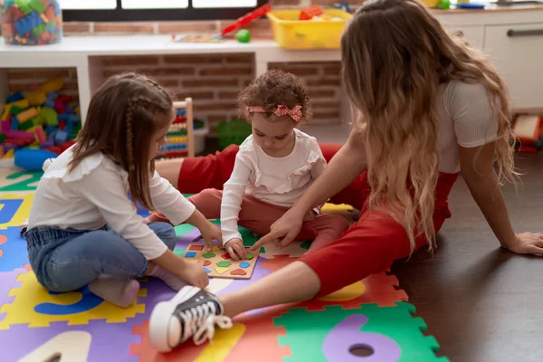 教師とともに女の子と遊ぶ数学パズルゲームは幼稚園で床に座って — ストック写真