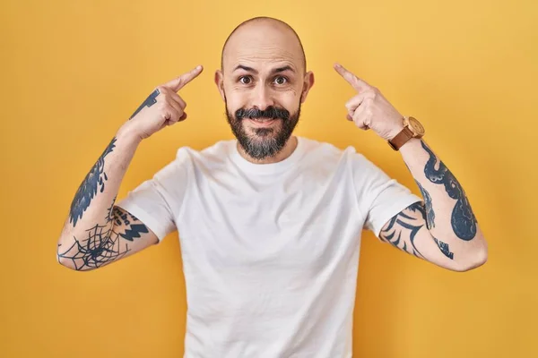 Young Hispanic Man Tattoos Standing Yellow Background Smiling Pointing Head — Stock Photo, Image