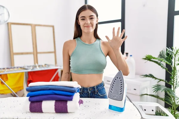 Young Hispanic Woman Ironing Clothes Laundry Room Showing Pointing Fingers — Fotografia de Stock