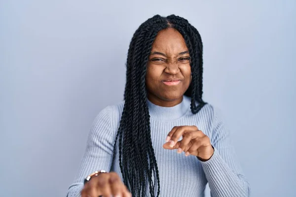 African american woman standing over blue background disgusted expression, displeased and fearful doing disgust face because aversion reaction.