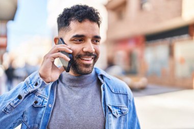 Genç İspanyol adam gülümsüyor. Kendine güveniyor. Sokakta akıllı telefondan konuşuyor.