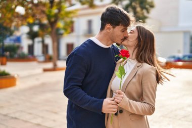 Mand and woman couple suprise with rose standing together at park