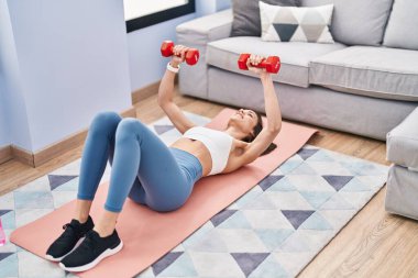 Young beautiful hispanic woman smiling confident training push up at home