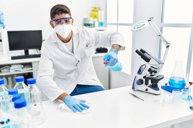 Laboratuvarda masayı bilimsel olarak temizleyen yakışıklı İspanyol adam.