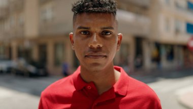 Young latin man with relaxed expression standing at street