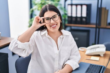 Ofiste çalışan genç İspanyol iş kadını laptopu kullanıyor.