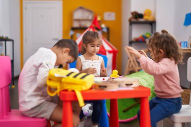Group of kids preschool students sitting on table drawing on paper at kindergarten