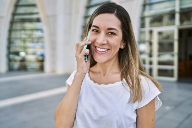 Genç İspanyol kadın gülümsüyor. Kendine güveniyor. Akıllı telefondan konuşuyor.
