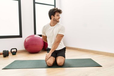 Genç İspanyol adam gülümsüyor spor merkezinde esniyor.