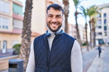 Sokakta kendinden emin gülümseyen İspanyol genç adam.