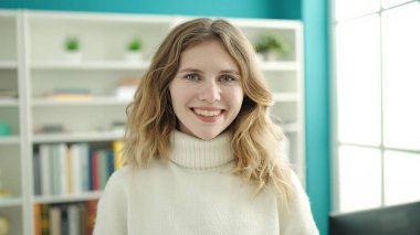 Young blonde woman student smiling confident standing at library university