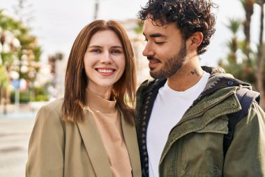 Kadın ve erkek gülümsüyor, sokakta birbirlerine sarılıyorlar.