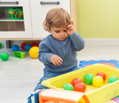 Sevimli İspanyol çocuk anaokulunda yerde oturmuş hayalarıyla oynuyor.