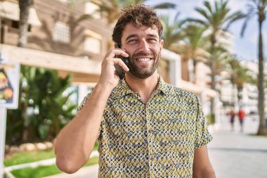 Genç İspanyol adam gülümsüyor. Kendine güveniyor. Sokakta akıllı telefondan konuşuyor.