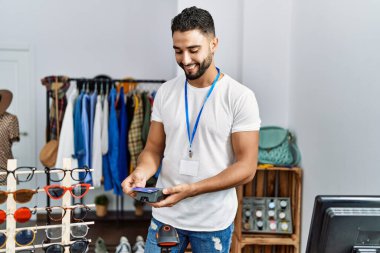 Genç Arap esnaf mağazasında kredi kartı ve veri telefonuyla ödeme yapıyor.