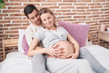 Kadın ve erkek yatak odasında birbirlerine sarılıyorlar.