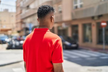 Young latin man standing on back view at street