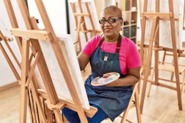 Kıdemli Afro-Amerikan kadın sanat stüdyosunda kendine güvenen çizimler yapıyor.