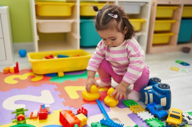 Adorable chinese toddler playing with ducks toys standing at kindergarten