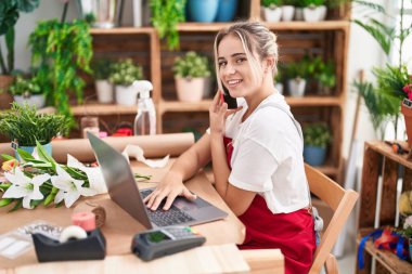 Çiçekçide bilgisayarla konuşan sarışın bir çiçekçi.