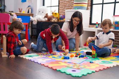 Anaokulunda yerde oturmuş matematik oyunu oynayan bir grup çocukla öğretmen.