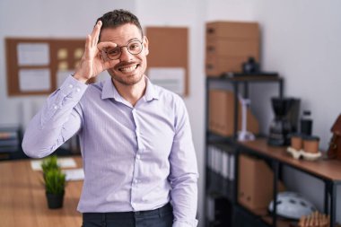 Ofisteki genç İspanyol adam el hareketleriyle gülümsüyor ve mutlu yüzüyle parmaklarının arasından bakıyor.. 