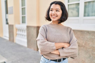 Young woman standing with arms crossed gesture looking to the side at street