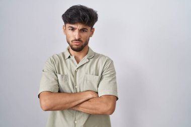 Arab man with beard standing over white background skeptic and nervous, disapproving expression on face with crossed arms. negative person. 