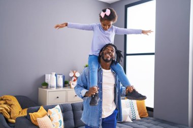Father and daughter smiling confident holding girl on shoulders at home