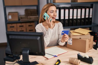 Genç kadın ecommerce busines ofis kredi kartı tutarak akıllı telefon konuşuyor