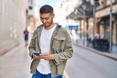 Sokakta akıllı telefon kullanan, kendine güvenen genç bir İspanyol.
