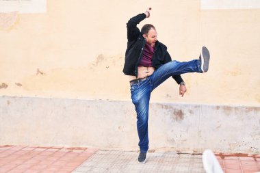 Young hispanic man smiling confident jumping at street