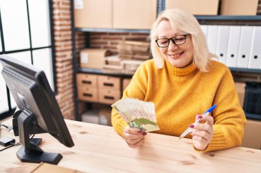Orta yaşlı sarışın kadın iş adamı Hong Kong dolarlarını sayıyor.