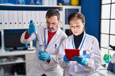 Laboratuvarda çalışan orta yaşlı erkek ve kadın bilim adamları