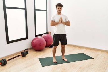 Genç İspanyol adam gülümsüyor spor merkezinde yoga antrenmanı yapıyor.