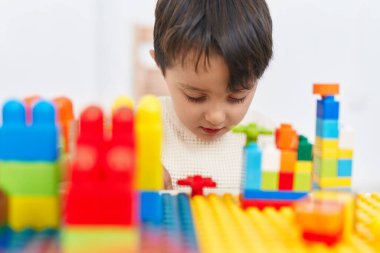 Anaokulundaki masada oturan, inşaat bloklarıyla oynayan sevimli İspanyol çocuk.
