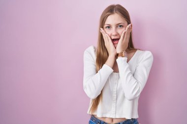 Pembe arka planda duran beyaz bir kadın. Korkmuş ve şok olmuş, şaşırmış ve hayrete düşmüş. 