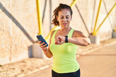 Orta yaşlı İspanyol kadın gezinti güvertesinde akıllı saatle çalışıyor.