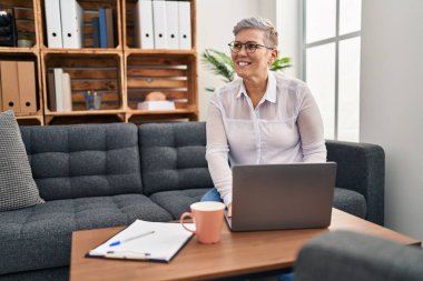 Orta yaşlı kadın psikolog, pischoloji merkezindeki koltukta oturuyor.